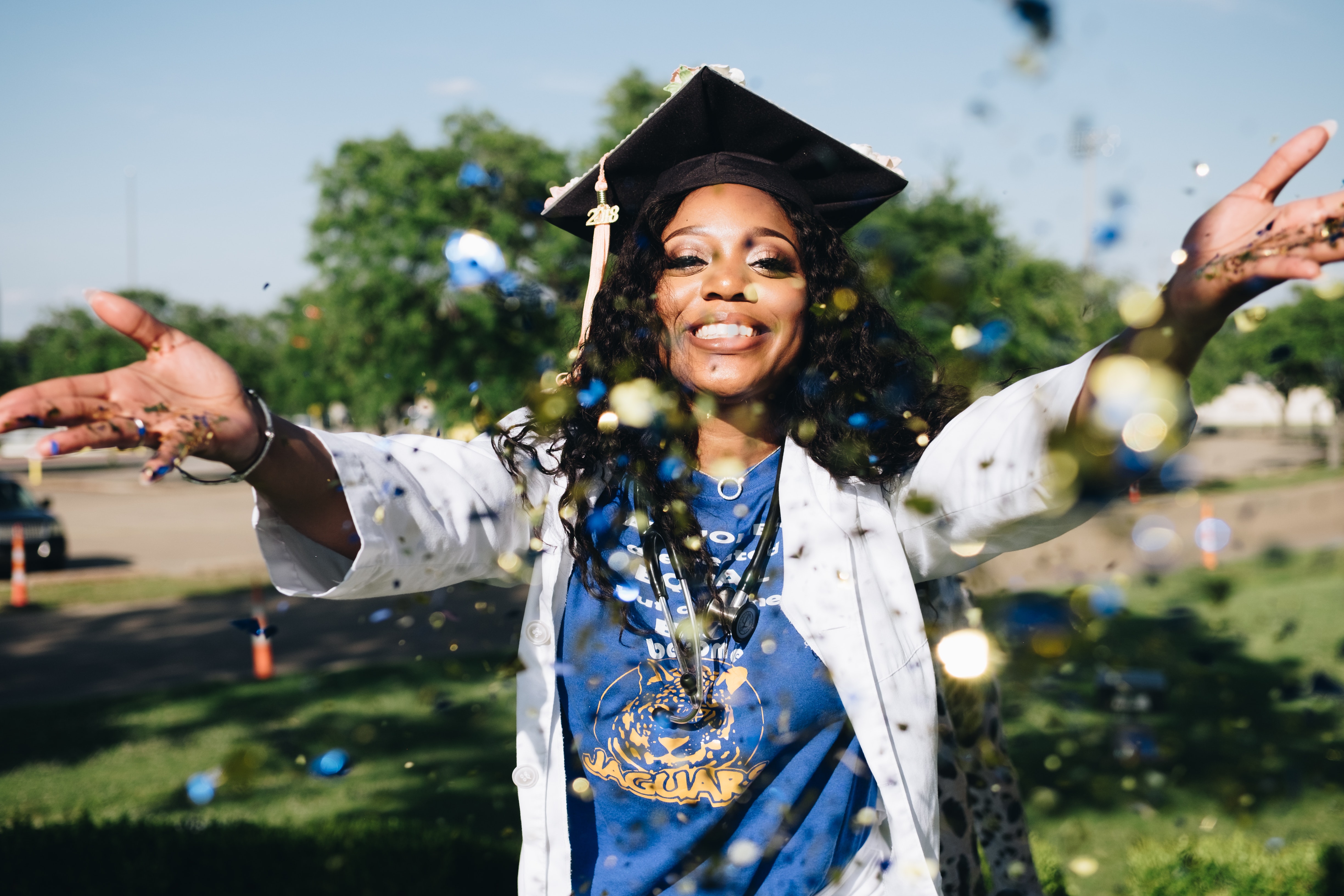 woman in graduation cap throwing confetti 